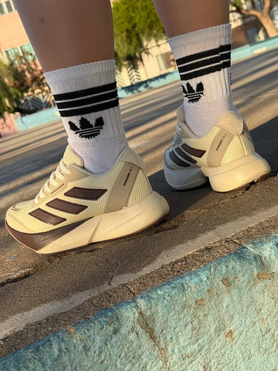 Adidas Adizero Adios Pro 4 off-white e vinho no pé, com meia branca, na calçada